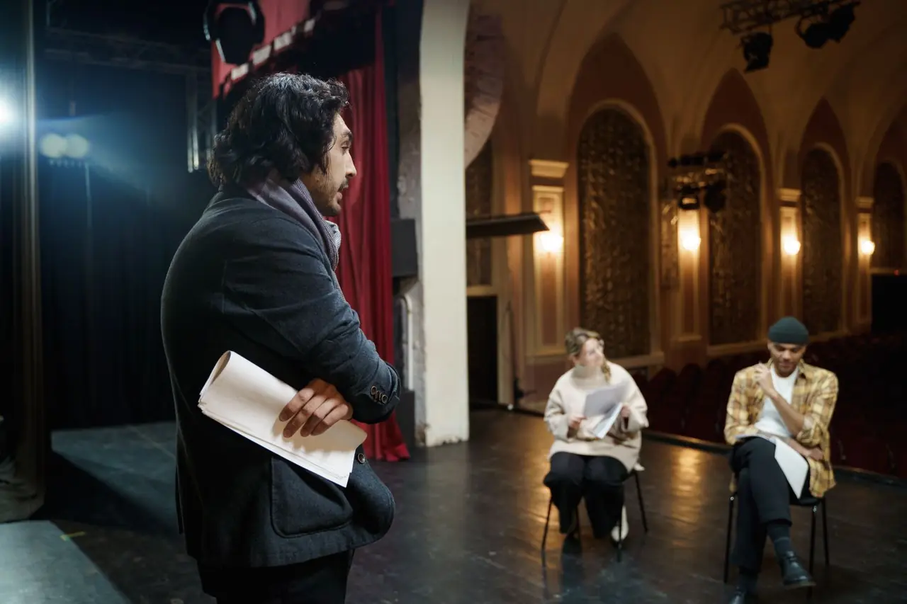 Näyttelijät harjoittelevat teatterin näyttämöllä ohjaajan seurassa